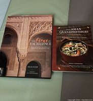 Photo showing two hardcover books: 'The Fires of Excellence' about Spanish and Portuguese oriental architecture, and 'The Asian Grandmothers Cookbook' focusing on home cooking from Asian American kitchens.
