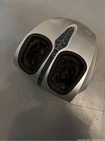 Foot massage machine top view showing two foot compartments with black lining and digital control panel with multiple buttons.