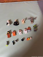 Collection of various LEGO minifigures and accessories spread out on a surface, showing Star Wars and Harry Potter characters with weapons and accessories.