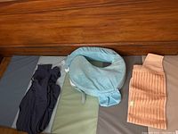 Photo showing the three items: black Boba newborn baby wrap, light blue nursing pillow, beige recovery support binder, all laid out on a surface.