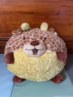 Front view of squishable giraffe plush on a wooden background