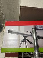 Telescope mounted on tripod displayed on the packaging box.