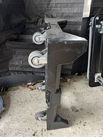 Side photo showing black plastic utility cart on its side, highlighting four caster wheels attached to the bottom for mobility.