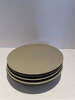 Stack of beige round plates photographed from front and side angles to show size and color.