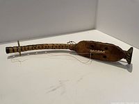 Full side view of the wooden African string instrument showing the decorated neck and the string attached.