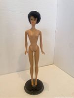Front view of the brunette bubblecut Barbie doll nude on a stand, showing the facial features and curly hair.