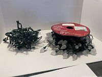 Clear leaf-shaped bulb Christmas lights on spool with black wire