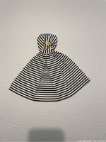 Front view of the vintage Barbie dress with navy blue horizontal stripes on white fabric, sleeveless and high neckline, lying flat with visible snap button closure at back.
