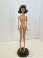 Full body shot of the vintage brunette Midge doll, nude, positioned on a black doll stand (stand not included).