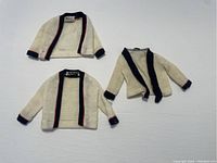 Front view of three vintage Ken doll jackets, two with black and red trim, one with black trim and patterned collar.