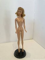 Full body photo of vintage Midge doll standing on a black round stand (stand not included). Doll is nude with fair complexion and blonde hair.