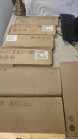 Photo showing seven keyboards in original brown shipping boxes stacked, some with HP labels visible, one keyboard out of box on right side