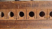 Close-up of wooden tobacco cigar press showing patent dates and hole patterns.