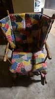 Front view of the child's wooden rocking chair with colorful patchwork cushioned seat and back cover.