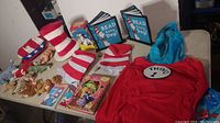 Wide view of table showing multiple Dr. Seuss themed items including Cat in the Hat hats, plush toys, picture frames and books.