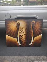 Front view of the large elephant artwork, showing detailed depiction of elephant face and tusks on canvas.