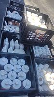 Eight black milk crates filled with white plastic 1-qt bottles and some boxed tubes