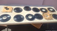 Table with approximately twelve black Edison phonograph records, some loose and some in worn original paper sleeves.