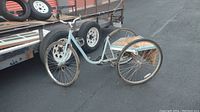 Full side view of vintage light blue three-wheel adult bicycle showing frame, wheels and structural condition.