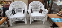 Two white wicker armchairs side-by-side, showing full front and side views.