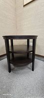 Front and side view of a round dark wood side table with two lower shelves, showing straight legs and wood grain finish.