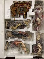 Styrofoam tray with multiple wrapped nativity figurines including animal and human figures, labeled with 'camello' for camel figurine