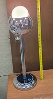 Side view of vintage chrome sphere table lamp with white frosted glass globe light shade and measuring tape showing approximately 17 inches tall