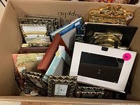 Top view of box showing a variety of picture frames inside, some with visible price tags.