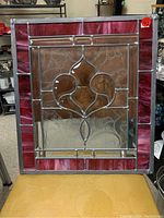 Front view of stained glass panel showing central brown floral design with clear and red glass border.