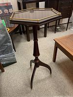 Side view of the hexagonal mahogany side table showing its brass gallery and tripod legs.
