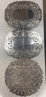 Three ornate silver plated expanding trivets stacked, one showing missing bottom poles ends