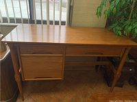 Full view of vintage solid wood desk showing overall shape, tapered legs, and wood finish.