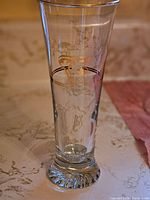 Close-up of one clear tall beer glass with Petro Canada Olympic etched logo and design on surface, tapered shape, thick base
