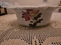 Side view of the white ceramic round casserole dish with floral pattern featuring pink and cream-colored flowers and green leaves.