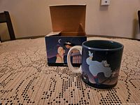 Photo showing Aladdin coffee mug with Genie artwork, original box behind