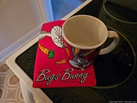 Photo of the Bugs Bunny ceramic coffee mug with matching napperon showing vibrant cartoon designs.