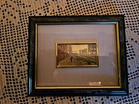 Framed decorative picture showing urban canal scene with buildings and a single pedestrian