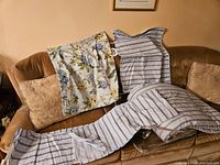 Full view of duvet cover and pillowcases laid out on a brown couch, showing blue and white stripes and floral patterns.