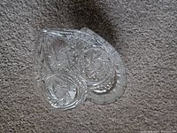 Top-down view of a clear heart shaped glass container with intricate star and leaf cut patterns on lid and base.