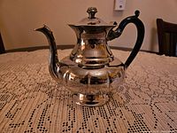 Photo of silver plated tea pot on lace tablecloth showing overall condition and design