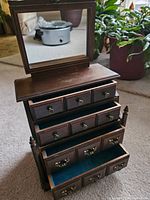 Open view of the jewellery box showing its hinged mirror and multiple drawers with blue felt lining.