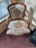 Front view of carved wooden frame chair with needlepoint upholstery