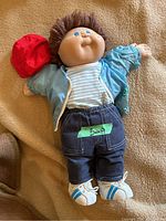 Front view of doll laid on beige blanket showing outfit and overall condition