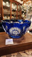 Front view of deep cobalt blue cut glass bowl showing scalloped rim and starburst pattern.