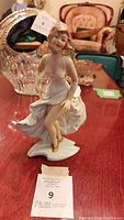 Front view of the porcelain figurine of a dancing woman in a flowing white dress, detailed face and gold shoes visible