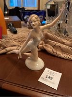 Porcelain figurine of a blonde ballerina in mid-pose on an oval base.