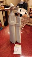 Front view of Lladro two nuns figurine showing ribbed glossy finish on a wooden table.