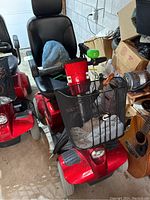 Front three-quarter view showing red body, padded seat, armrests and front wire basket