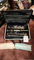 Open case showing disassembled clarinet joints, barrel, bell, mouthpiece and paperwork