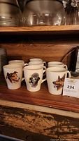 Group photo showing all 7 white ceramic dog mugs with visible dog portraits, placed on a wooden shelf.